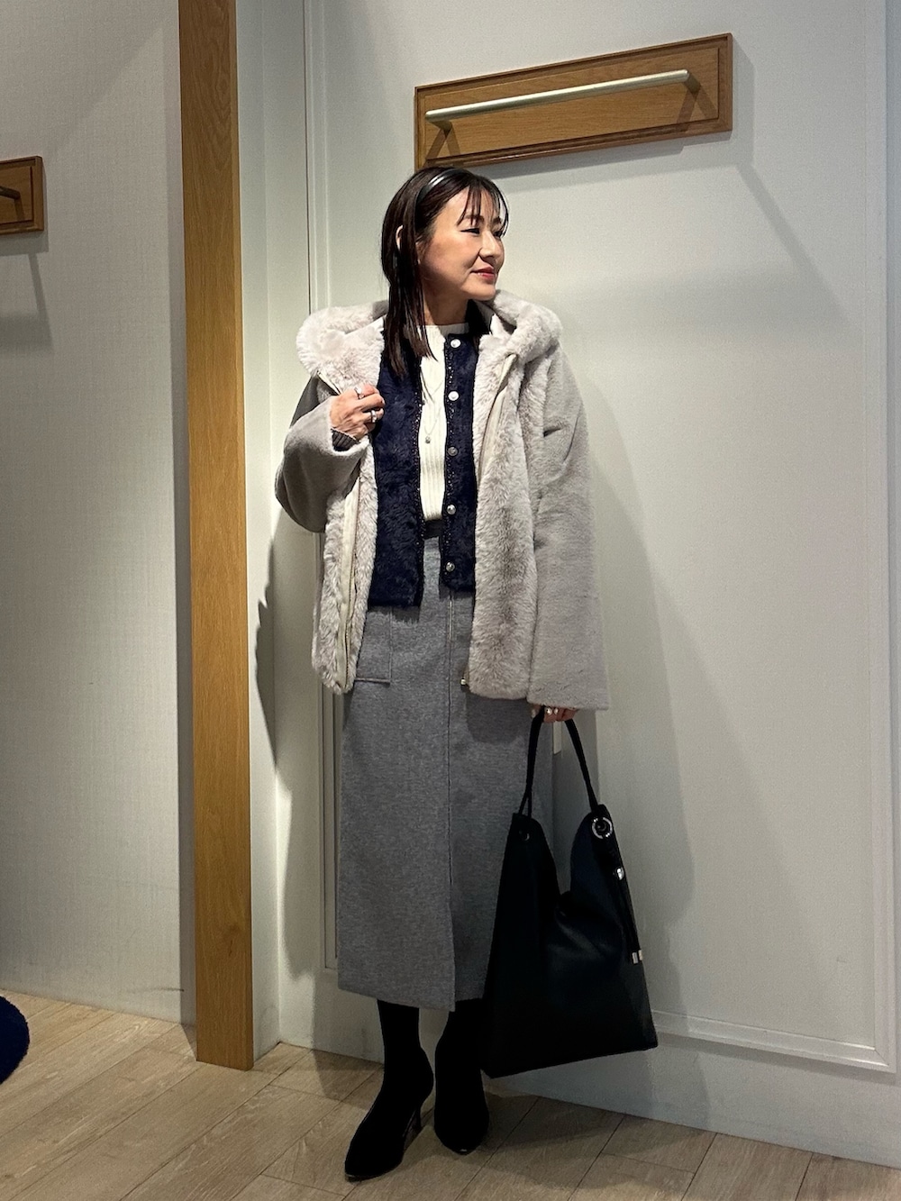 ベージュ系のムートンコート、ブルー系のニット/セーター、ホワイト系のニット/セーターを着用したレディースの冬コーディネートの5枚目の写真