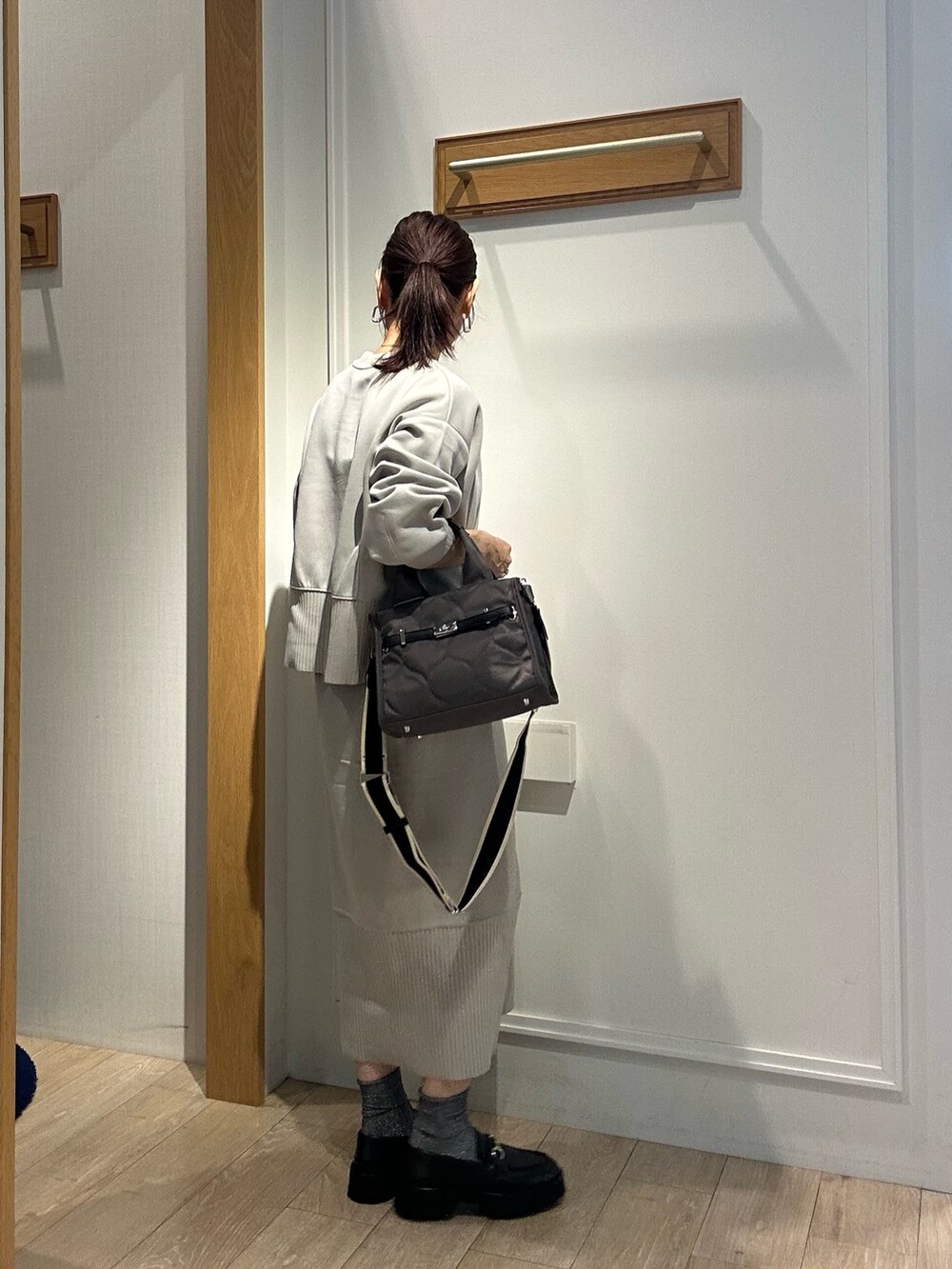 グレー系のトートバッグ、ベージュ系のスカート、ベージュ系のTシャツ/カットソーを着用したレディースの秋コーディネートの3枚目の写真