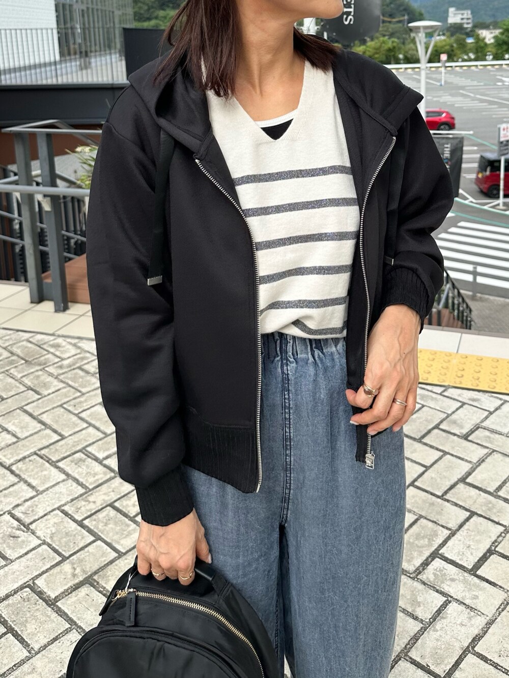 ブラック系のパーカー、ブルー系のデニムパンツ、ブラック系のバックパック/リュックを着用したレディースの秋コーディネートの6枚目の写真