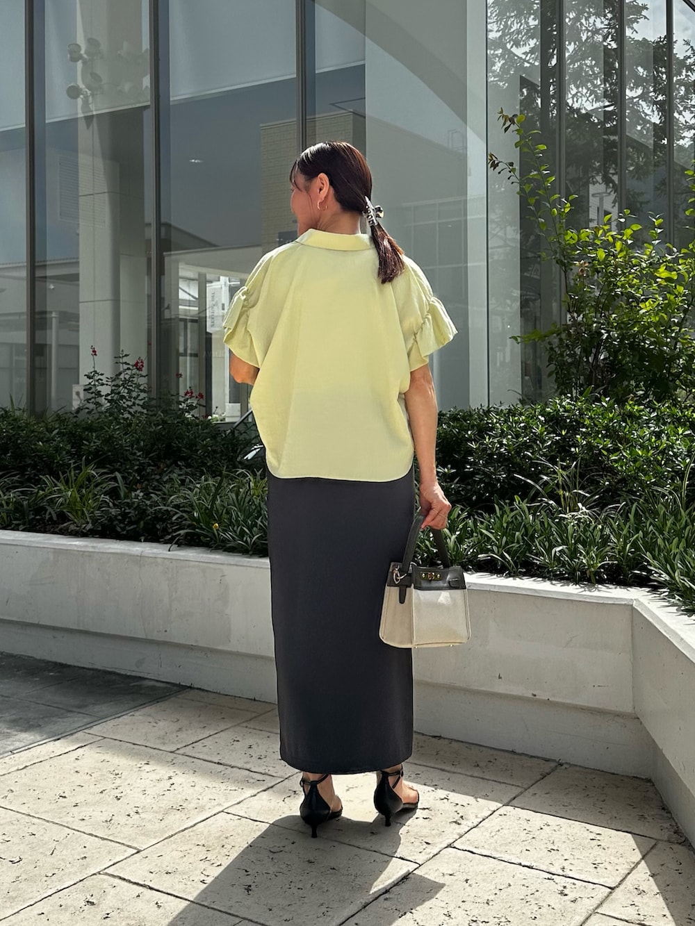 イエロー系のシャツ/ブラウス、ホワイト系のTシャツ/カットソー、グレー系のスカートを着用したレディースの夏コーディネートの3枚目の写真