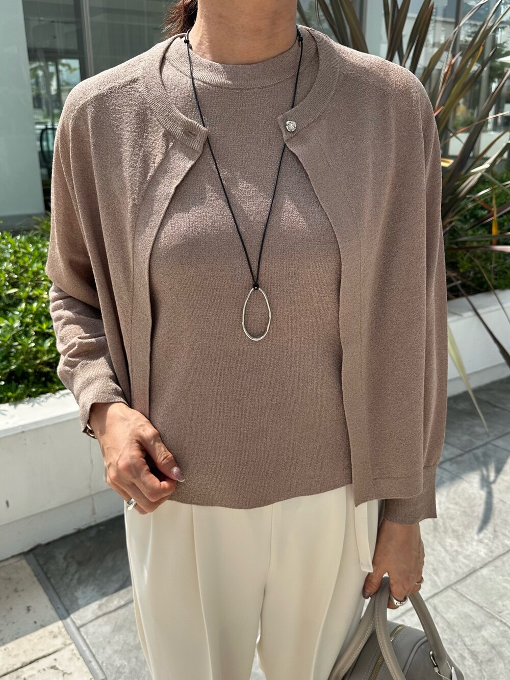 ブラウン系のニット/セーター、ホワイト系のその他パンツ、ベージュ系のボストンバッグを着用したレディースの夏コーディネートの6枚目の写真