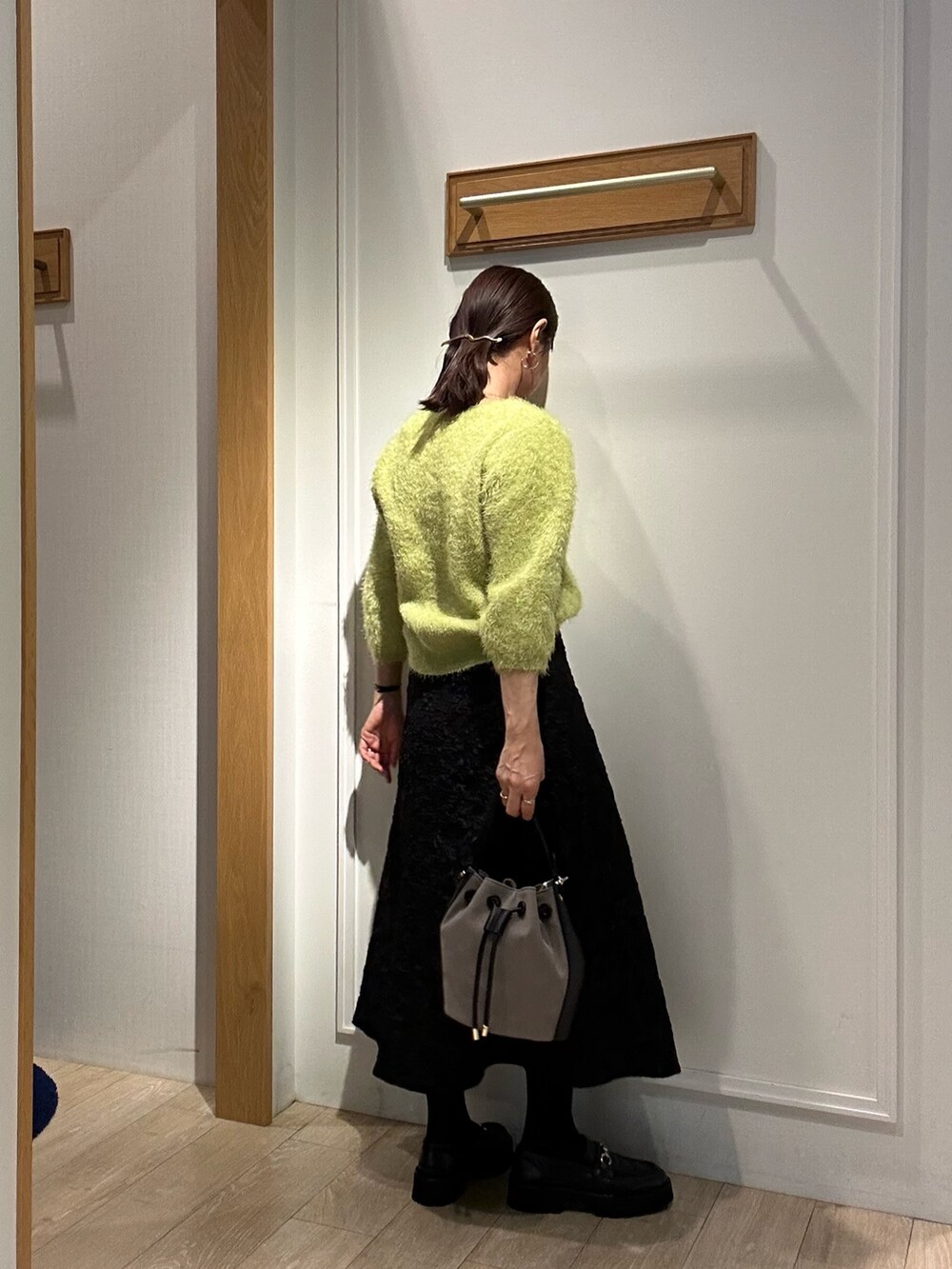 グリーン系のニット/セーター、グレー系のスカート、イエロー系のブルゾンを着用したレディースの秋コーディネートの3枚目の写真
