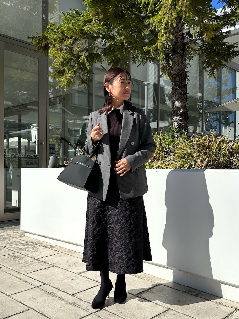 ブラック系のトートバッグ、グレー系のテーラードジャケット、ブラック系のニット/セーターを着用したレディースの秋コーディネートの7枚目の写真