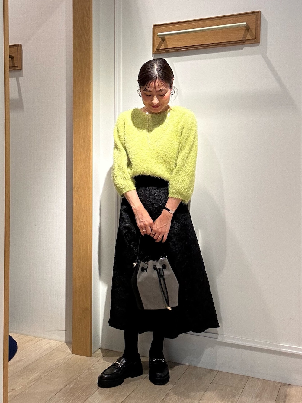 グリーン系のニット/セーター、グレー系のスカート、イエロー系のブルゾンを着用したレディースの秋コーディネートの4枚目の写真
