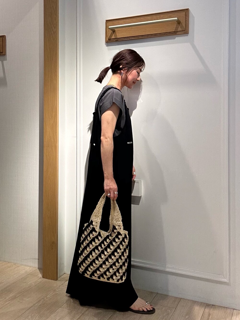 ブラック系のワンピース、ホワイト系のカーディガン/ボレロ、ゴールド系のネックレスを着用したレディースの夏コーディネートの4枚目の写真