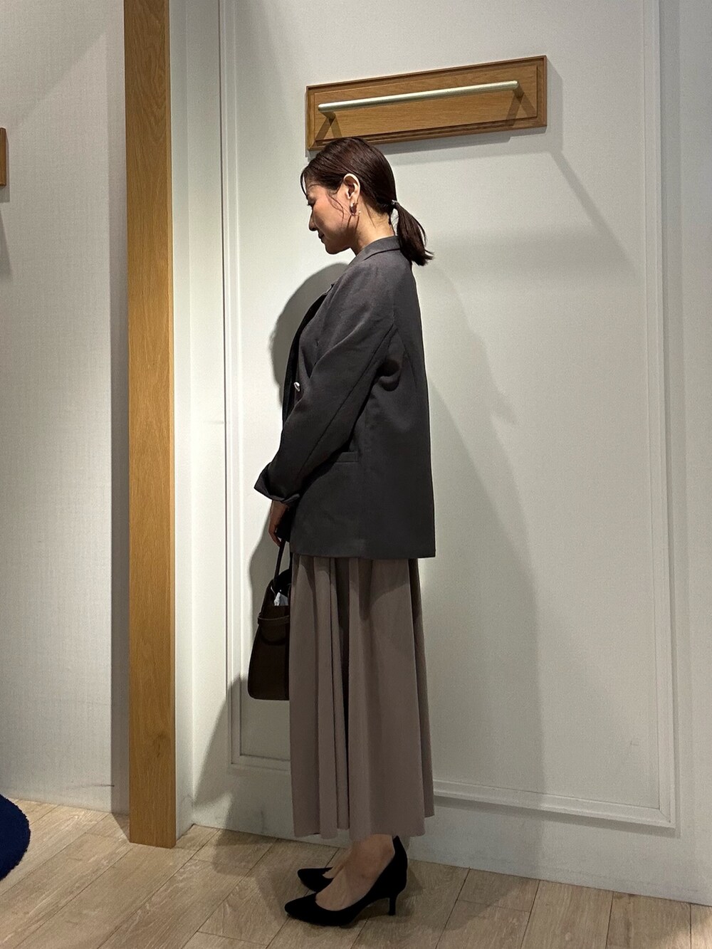 グレー系のテーラードジャケット、ブラウン系のスカート、ブルー系のシャツ/ブラウスを着用したレディースの秋コーディネートの2枚目の写真