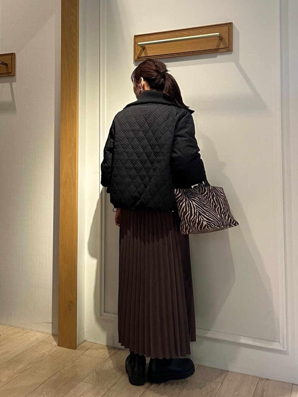 ブラウン系のブルゾン、ホワイト系のニット/セーター、ブラウン系のスカートを着用したレディースの秋コーディネートの4枚目の写真