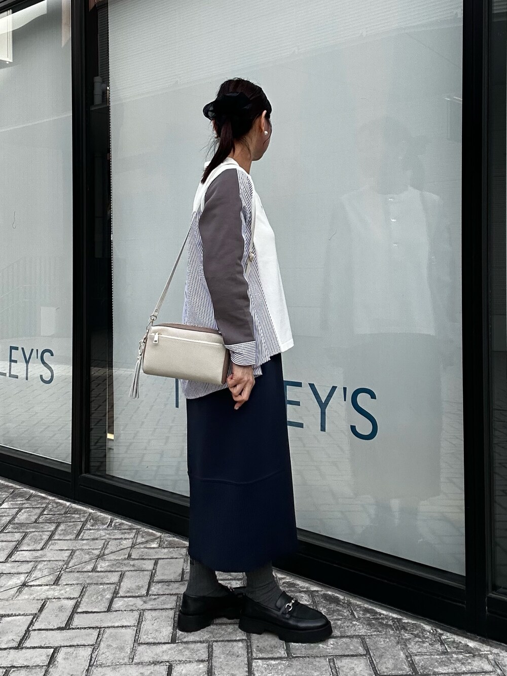 ブルー系のスカート、ホワイト系のニット/セーター、ホワイト系のショルダーバッグを着用したレディースの冬コーディネートの4枚目の写真