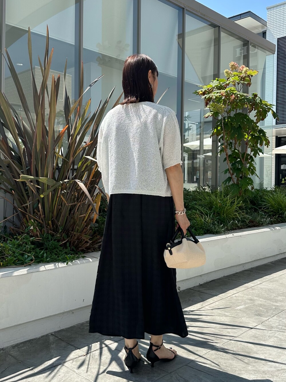 ブラック系のワンピース、ホワイト系のカーディガン/ボレロ、ブラック系のバックパック/リュックを着用したレディースの夏コーディネートの3枚目の写真