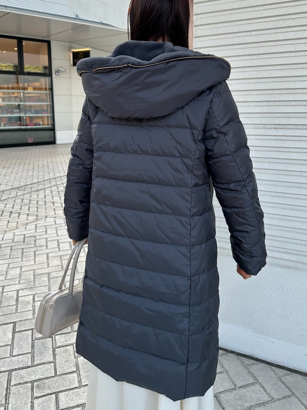 ピンク系のニット/セーター、グレー系のダウンジャケット/コート、ホワイト系のスカートを着用したレディースの冬コーディネートの6枚目の写真