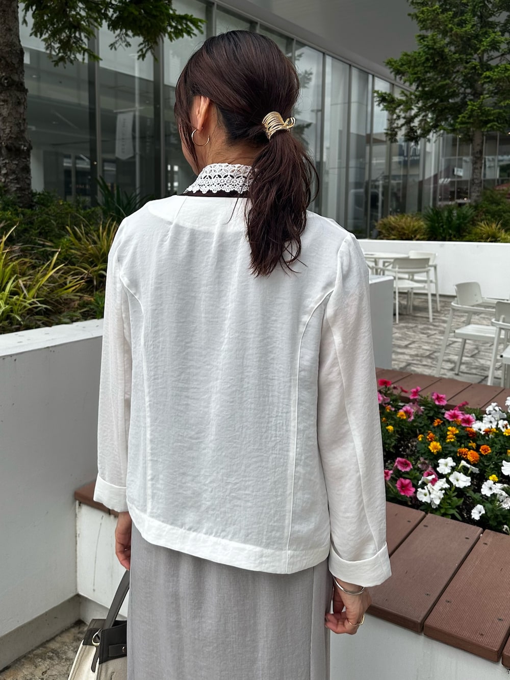 ホワイト系のノーカラージャケット、ブラウン系のTシャツ/カットソー、グレー系のスカートを着用したレディースの夏コーディネートの6枚目の写真