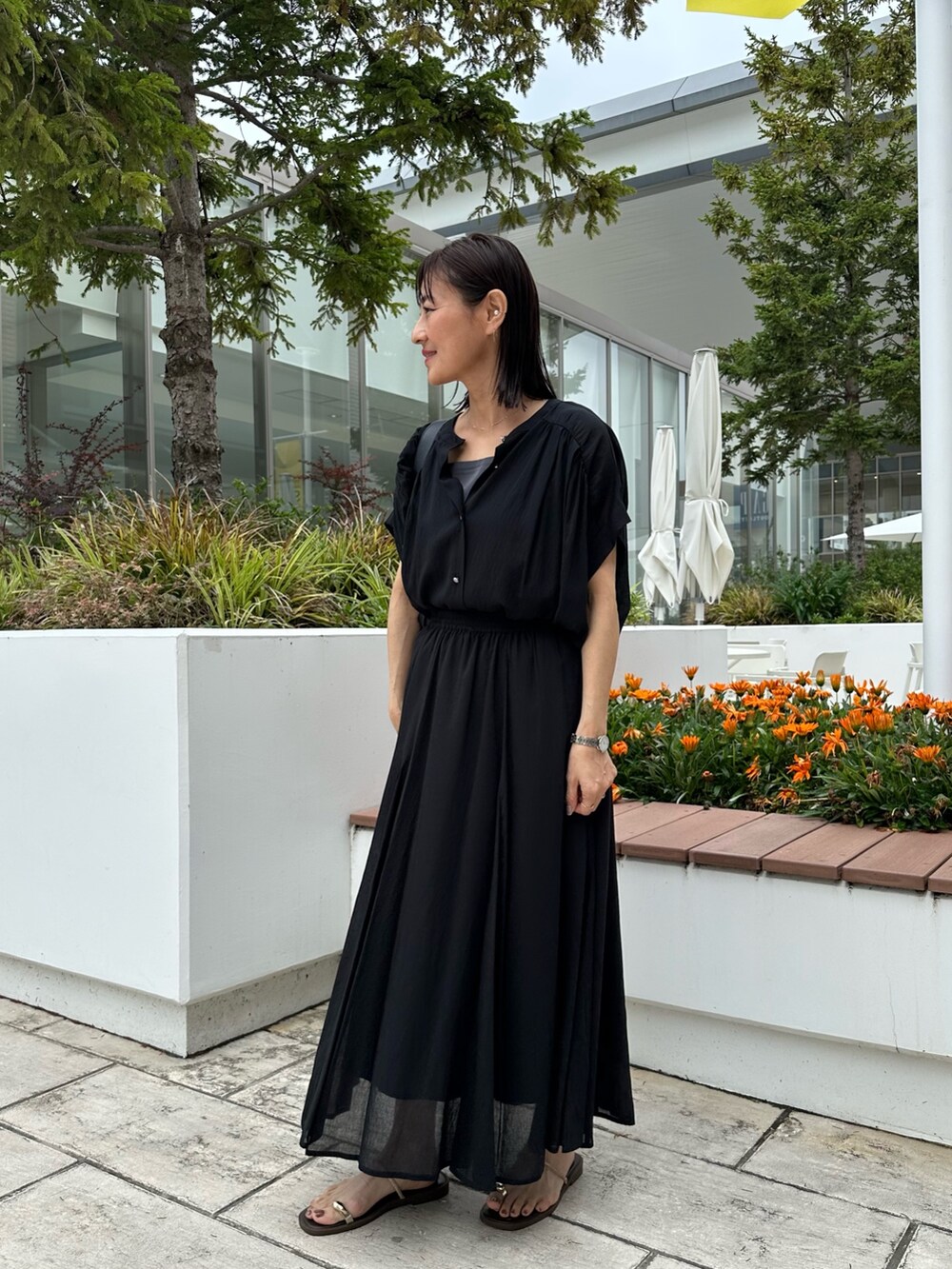 ブラック系のシャツ/ブラウス、ブラック系のスカート、ゴールド系のネックレスを着用したレディースの夏コーディネートの2枚目の写真