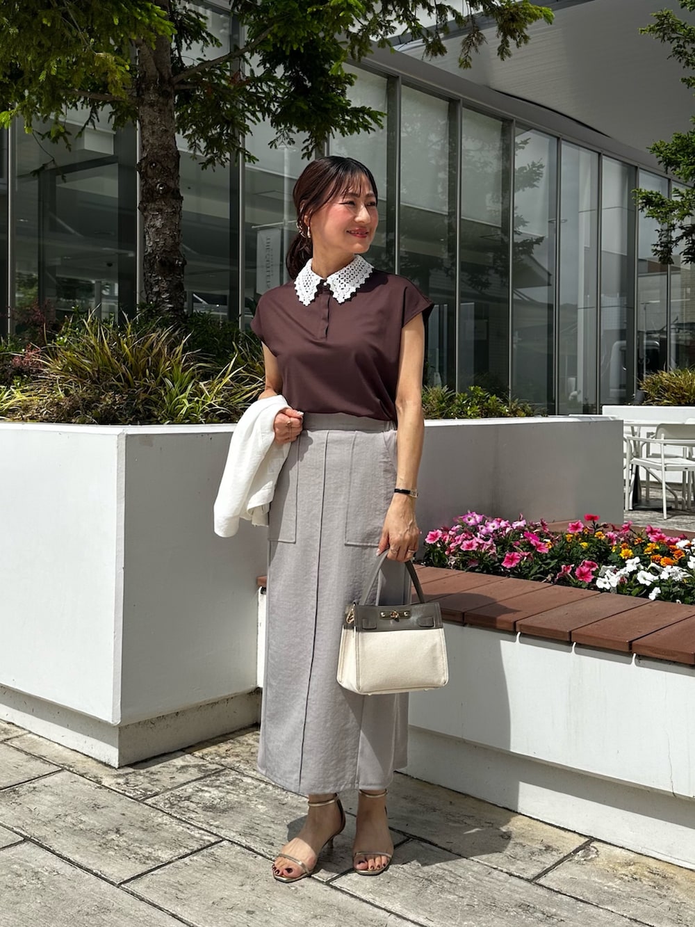 ホワイト系のノーカラージャケット、ブラウン系のTシャツ/カットソー、グレー系のスカートを着用したレディースの夏コーディネートの7枚目の写真