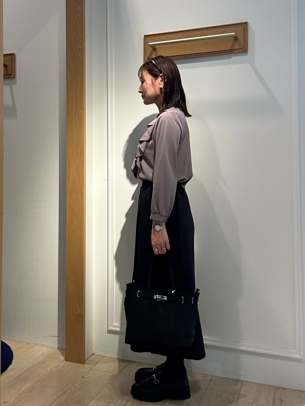 ブラウン系のシャツ/ブラウス、ブラック系のスカート、ブラック系のトートバッグを着用したレディースの秋コーディネートの2枚目の写真