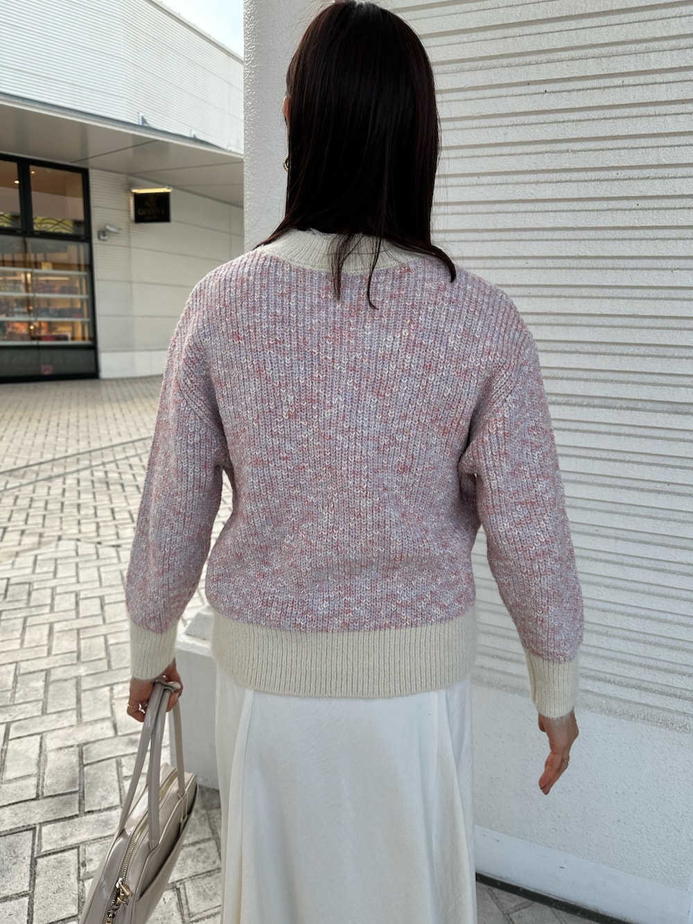 ピンク系のニット/セーター、ホワイト系のスカート、ホワイト系のボストンバッグを着用したレディースの冬コーディネートの7枚目の写真