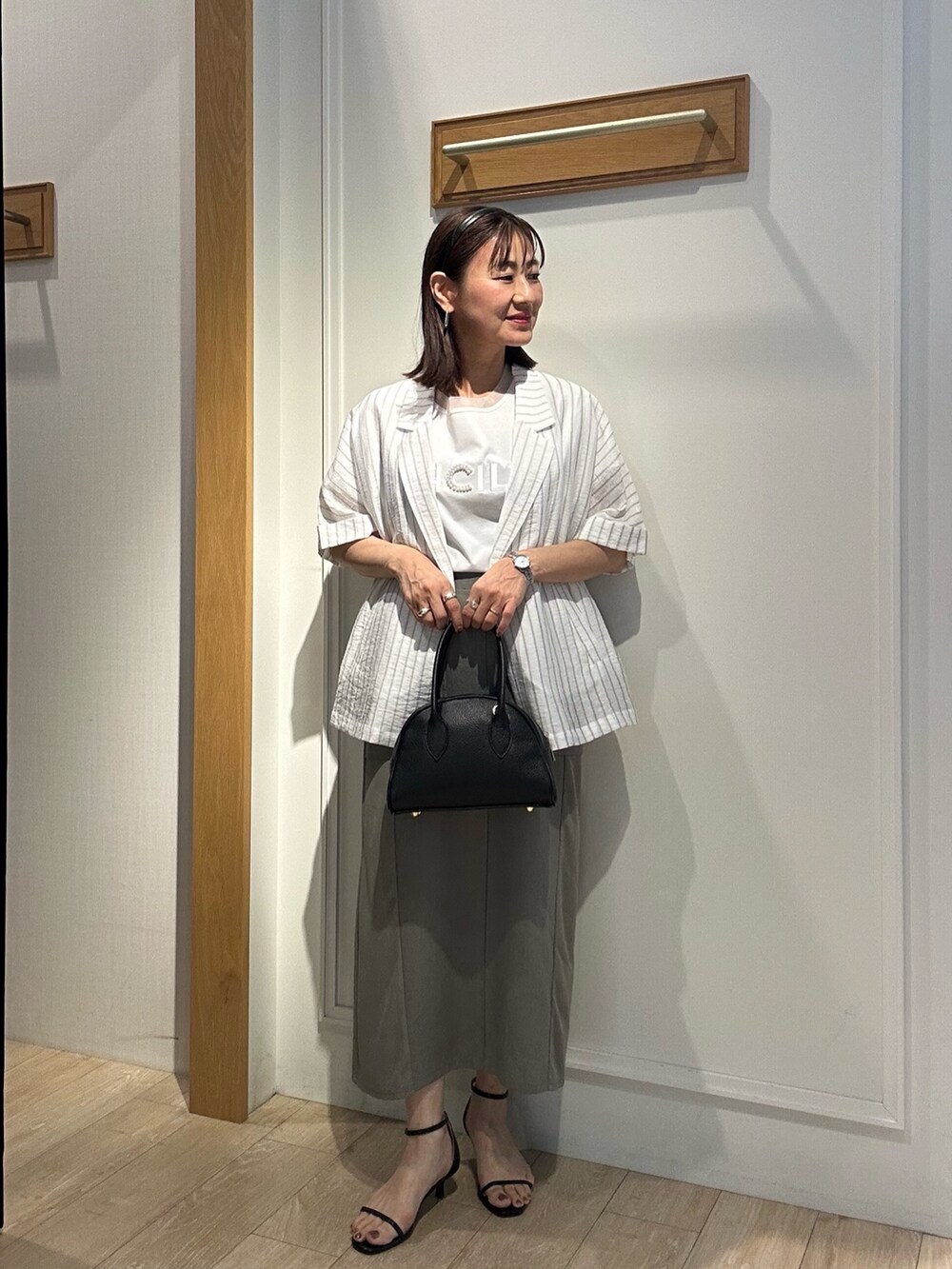 グレー系のテーラードジャケット、ホワイト系のTシャツ/カットソー、グリーン系のスカートを着用したレディースの夏コーディネートの4枚目の写真