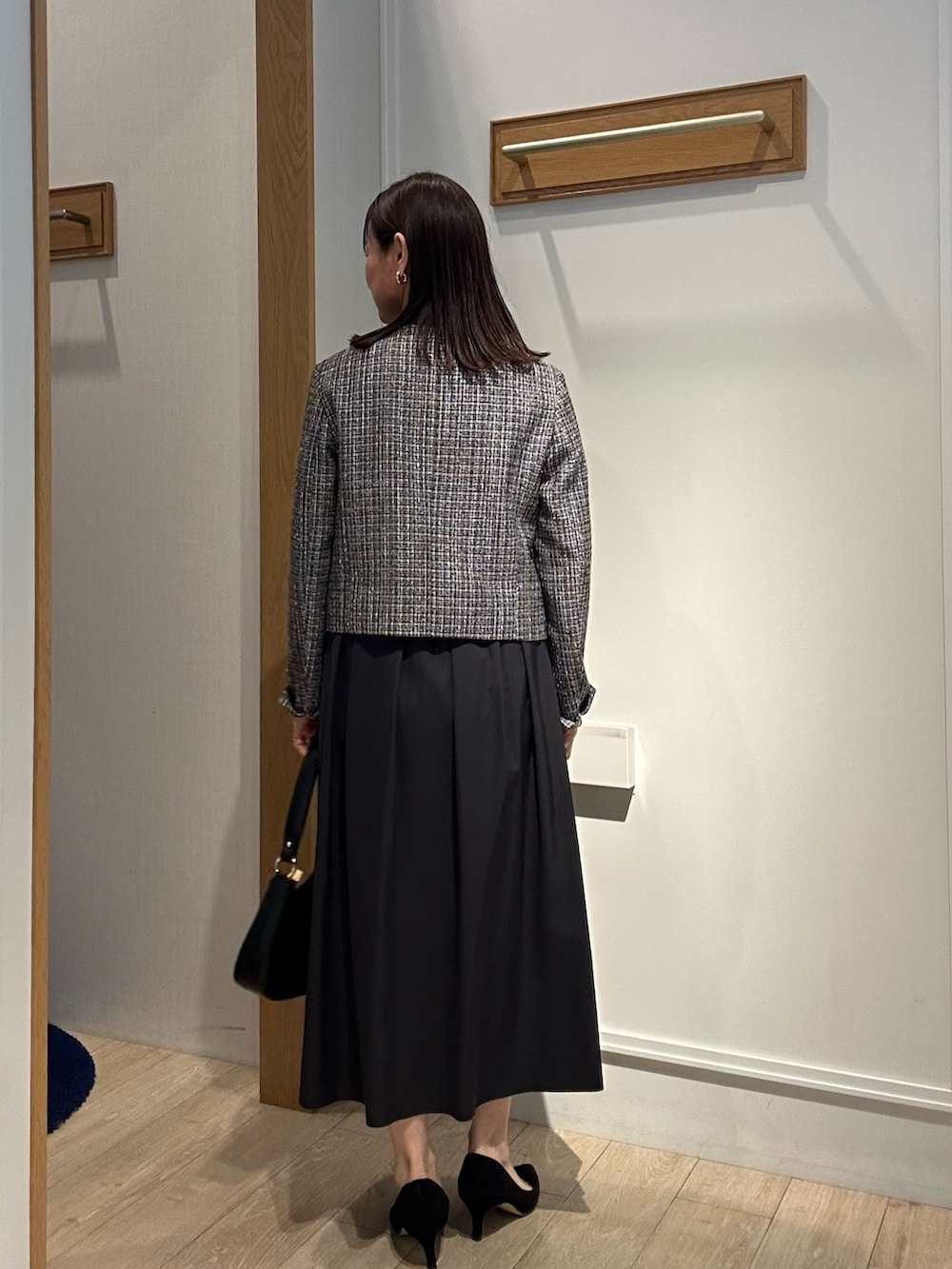 ブラック系のノーカラージャケット、ブラック系のTシャツ/カットソー、ブルー系のスカートを着用したレディースの冬コーディネートの3枚目の写真