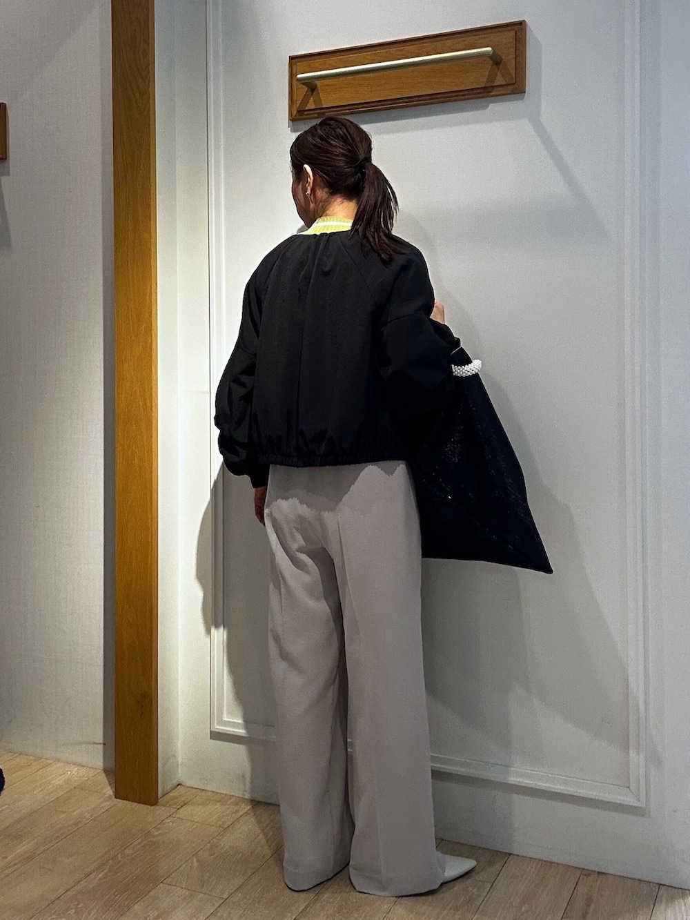 ベージュ系のその他パンツ、イエロー系のカーディガン/ボレロ、ブラック系のブルゾンを着用したレディースの春コーディネートの3枚目の写真