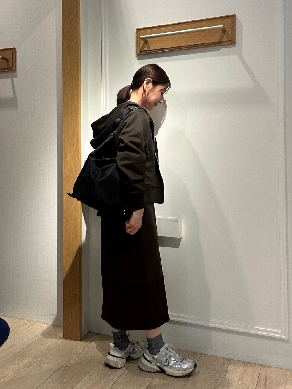 ブラウン系のパーカー、ブラウン系のスカート、ブラック系のショルダーバッグを着用したレディースの秋コーディネートの2枚目の写真