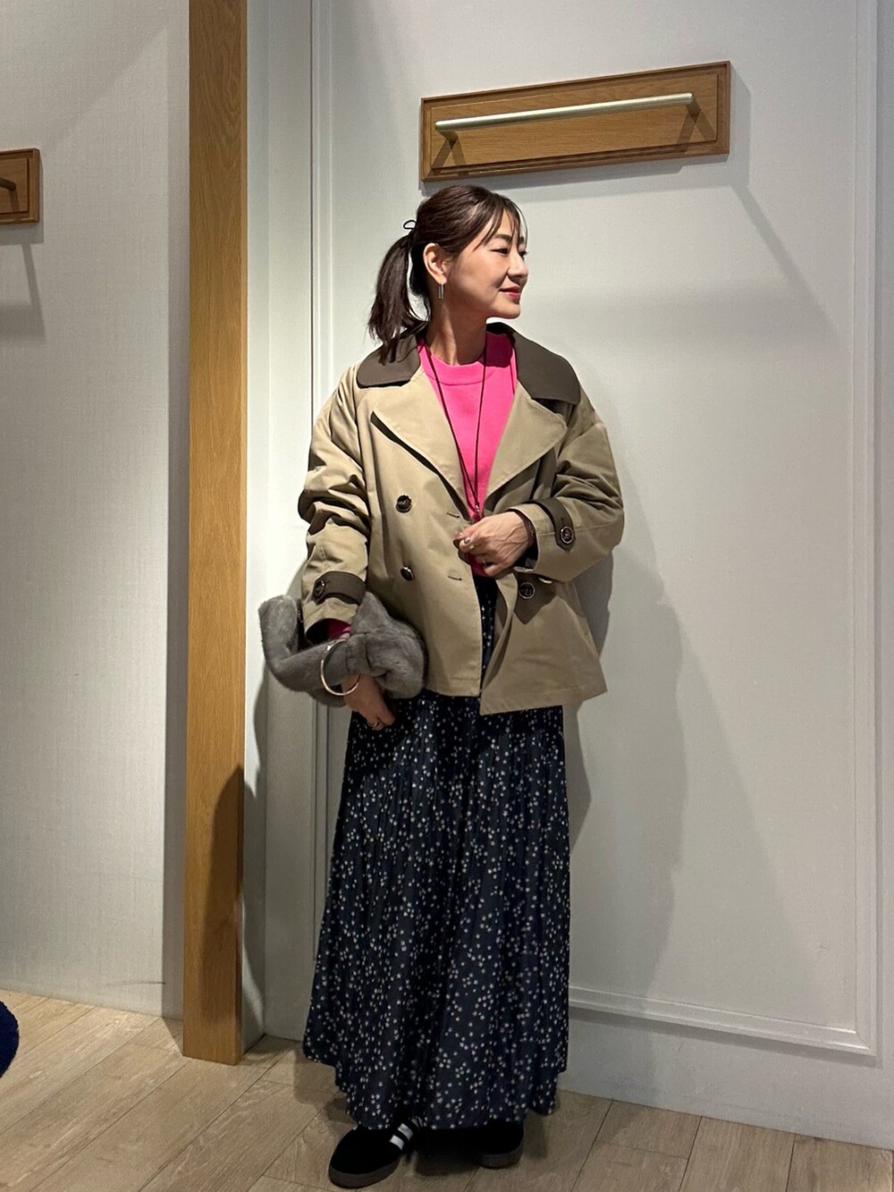 イエロー系のトレンチコート、ピンク系のニット/セーターを着用したレディースの秋コーディネートの2枚目の写真