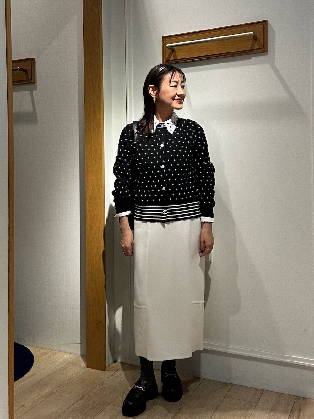 ブラック系のニット/セーター、ブラック系のショルダーバッグ、ホワイト系のシャツ/ブラウスを着用したレディースの冬コーディネートの5枚目の写真