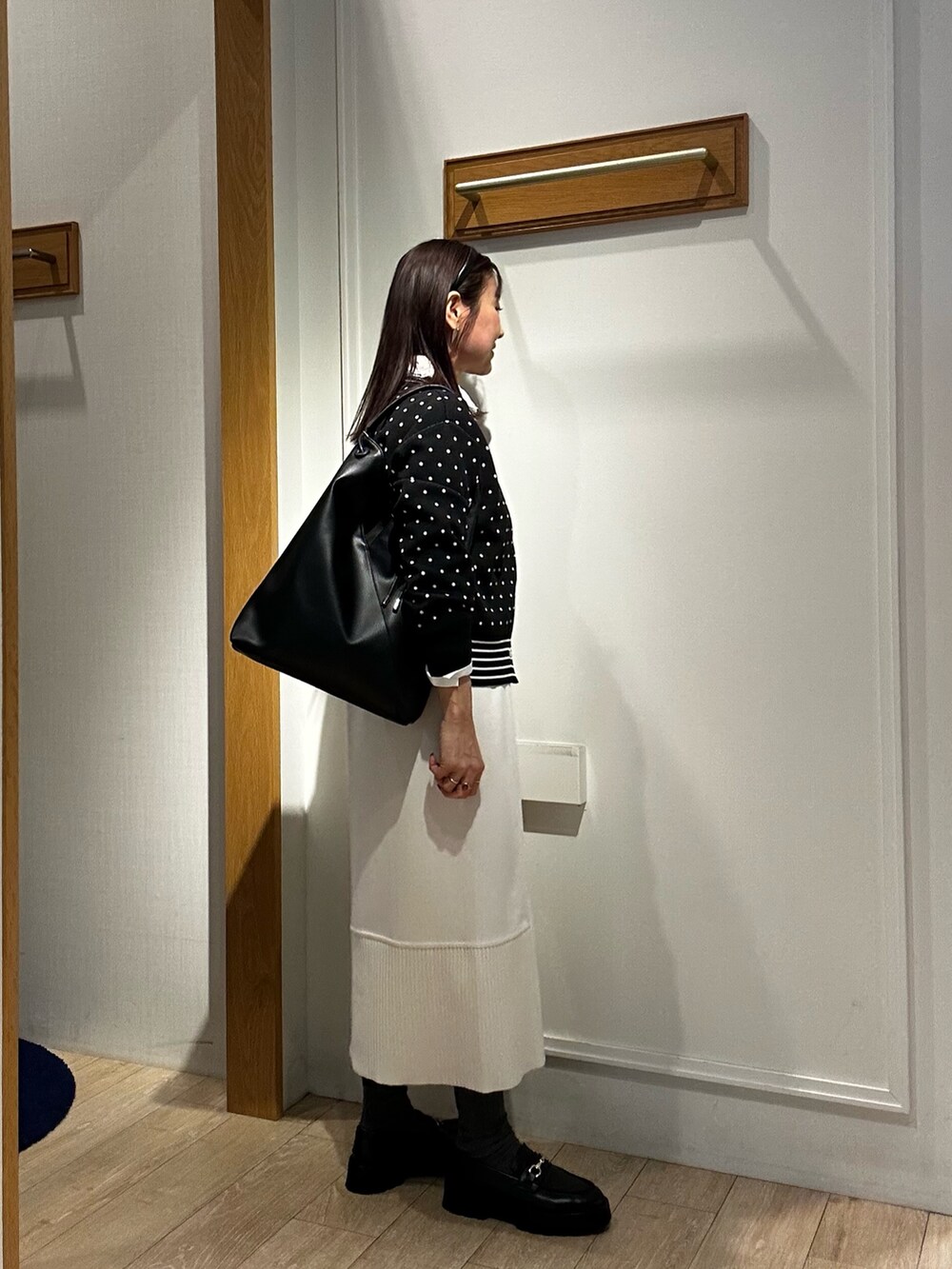 ブラック系のニット/セーター、ブラック系のショルダーバッグ、ホワイト系のシャツ/ブラウスを着用したレディースの冬コーディネートの4枚目の写真