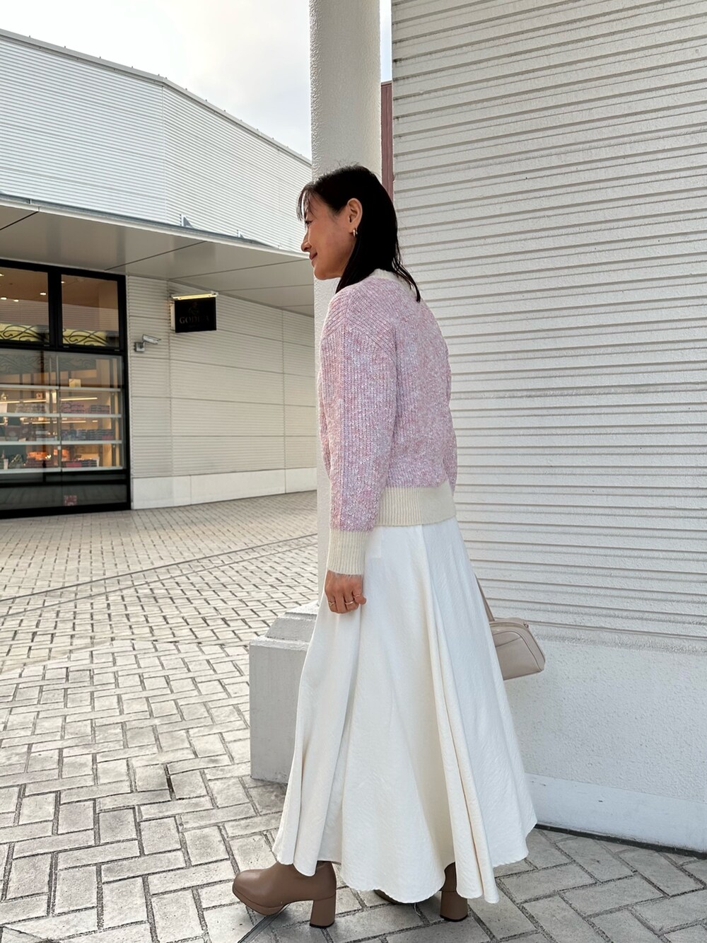 ピンク系のニット/セーター、ホワイト系のスカート、ホワイト系のボストンバッグを着用したレディースの冬コーディネートの3枚目の写真