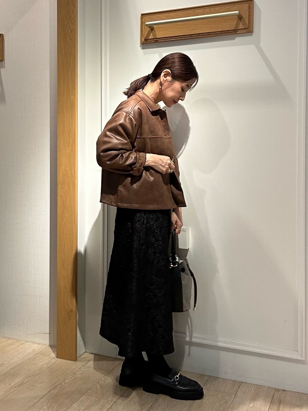 グリーン系のニット/セーター、グレー系のスカート、イエロー系のブルゾンを着用したレディースの秋コーディネートの10枚目の写真