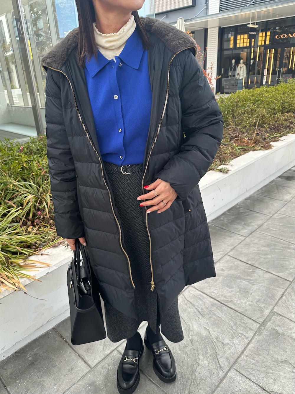 ブラウン系のローファー、ブラック系のダウンジャケット/コート、ブルー系のカーディガン/ボレロを着用したレディースの冬コーディネートの8枚目の写真