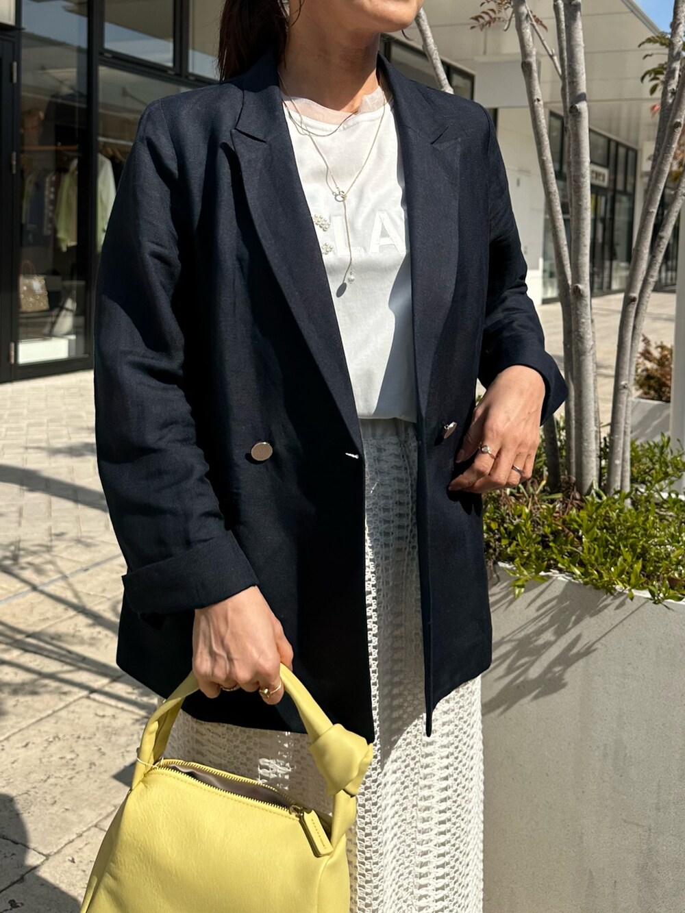 ブルー系のテーラードジャケット、ホワイト系のスカート、イエロー系のショルダーバッグを着用したレディースの春コーディネートの5枚目の写真