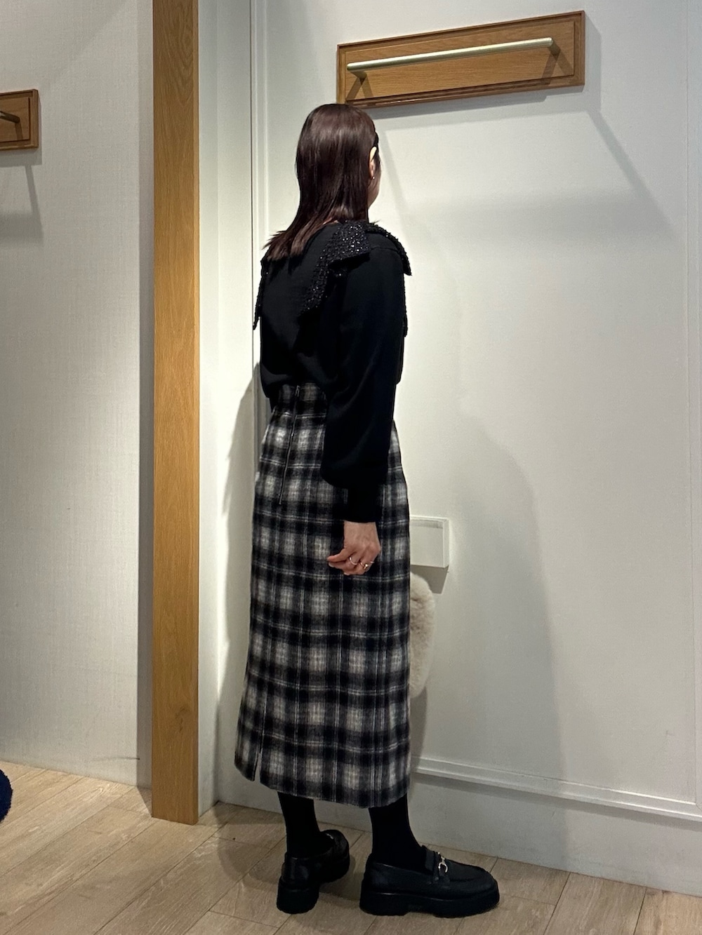 ブラック系のニット/セーター、ブルー系のスカート、ホワイト系のトートバッグを着用したレディースの冬コーディネートの3枚目の写真