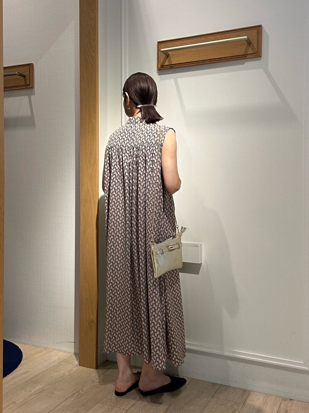 ベージュ系のワンピース、ホワイト系のカーディガン/ボレロ、ゴールド系のショルダーバッグを着用したレディースの春コーディネートの2枚目の写真