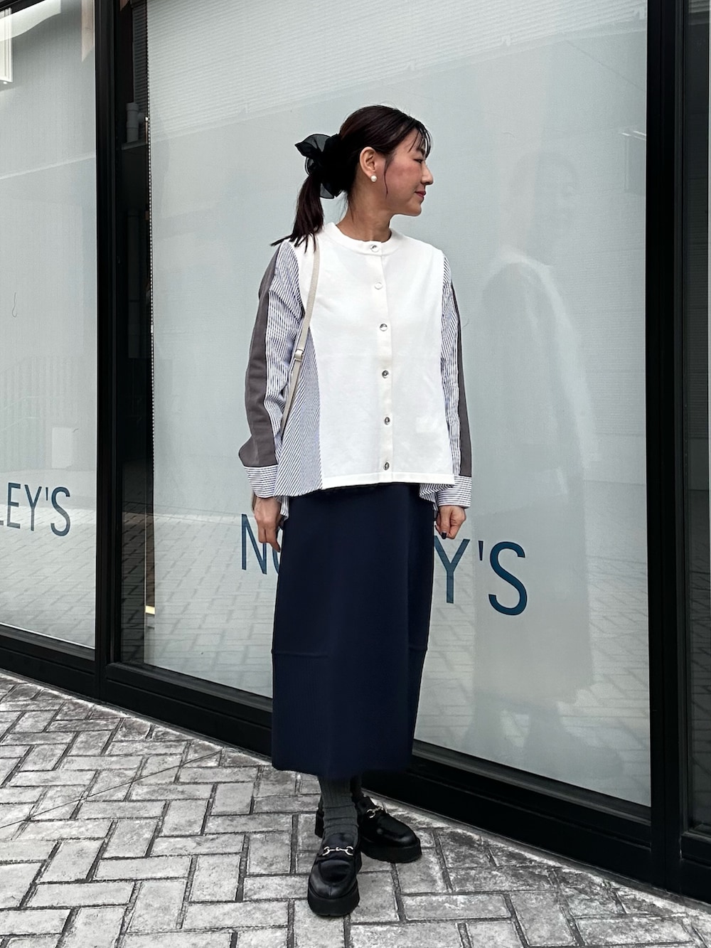 ブルー系のスカート、ホワイト系のニット/セーター、ホワイト系のショルダーバッグを着用したレディースの冬コーディネートの5枚目の写真