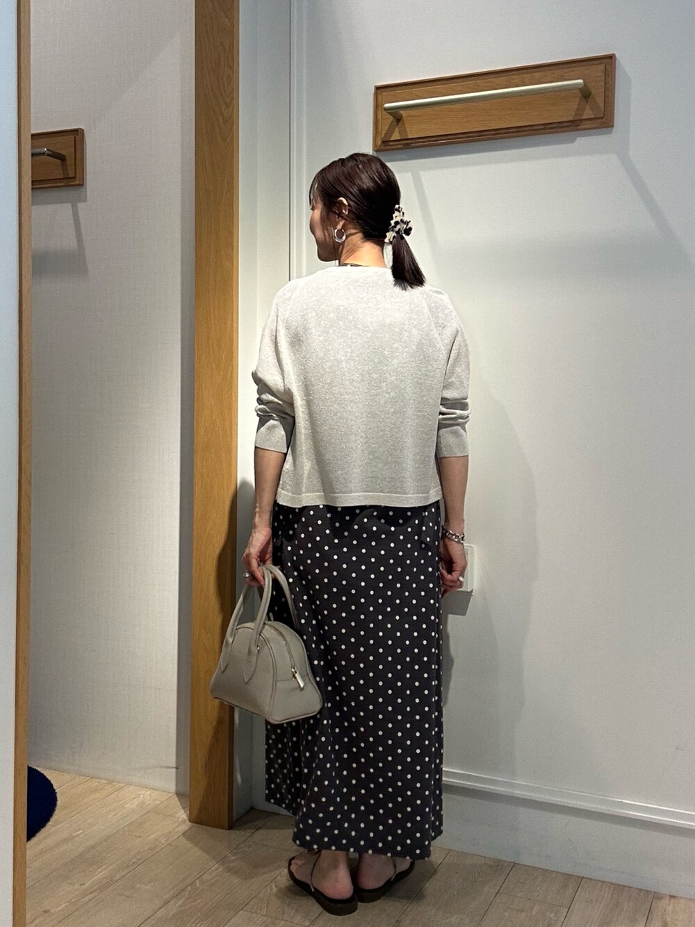 シルバー系のニット/セーター、グレー系のワンピース、ベージュ系のボストンバッグを着用したレディースの夏コーディネートの3枚目の写真