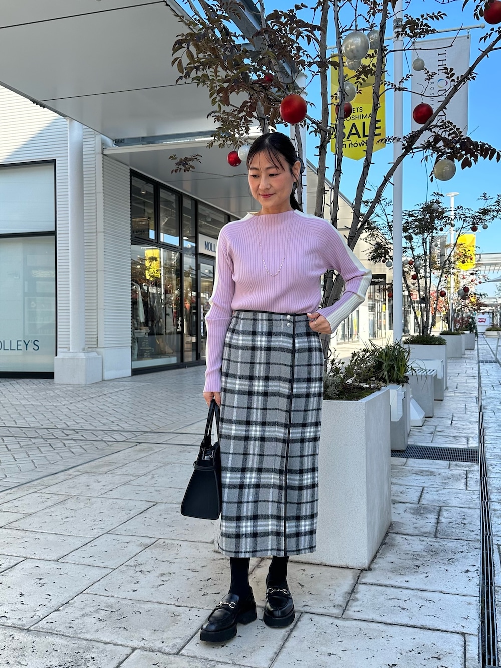 グレー系のスカート、ブラック系のトートバッグ、ピンク系のニット/セーターを着用したレディースの秋コーディネートの2枚目の写真