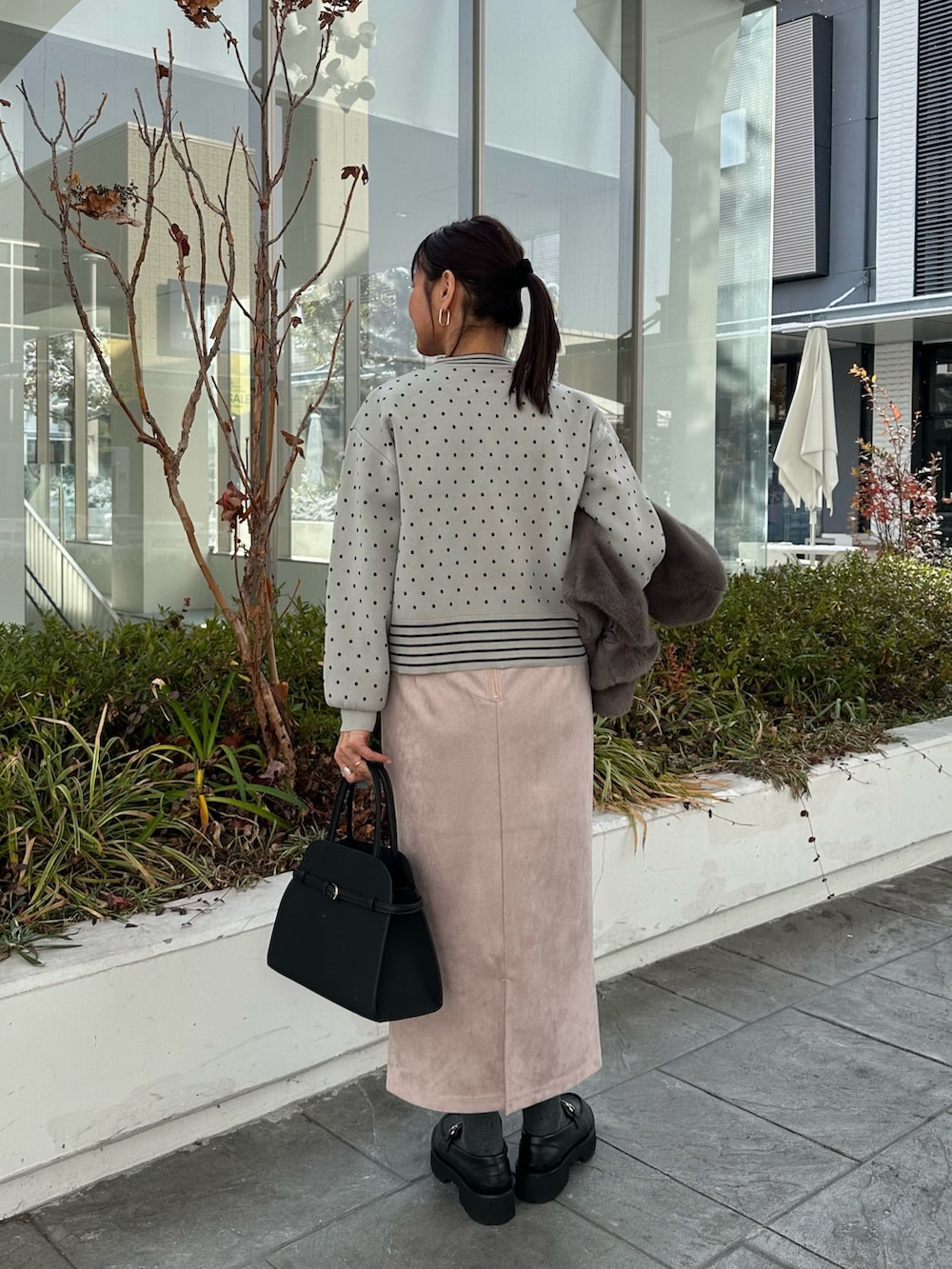 グレー系のブルゾン、グレー系のニット/セーター、ピンク系のスカートを着用したレディースの冬コーディネートの9枚目の写真