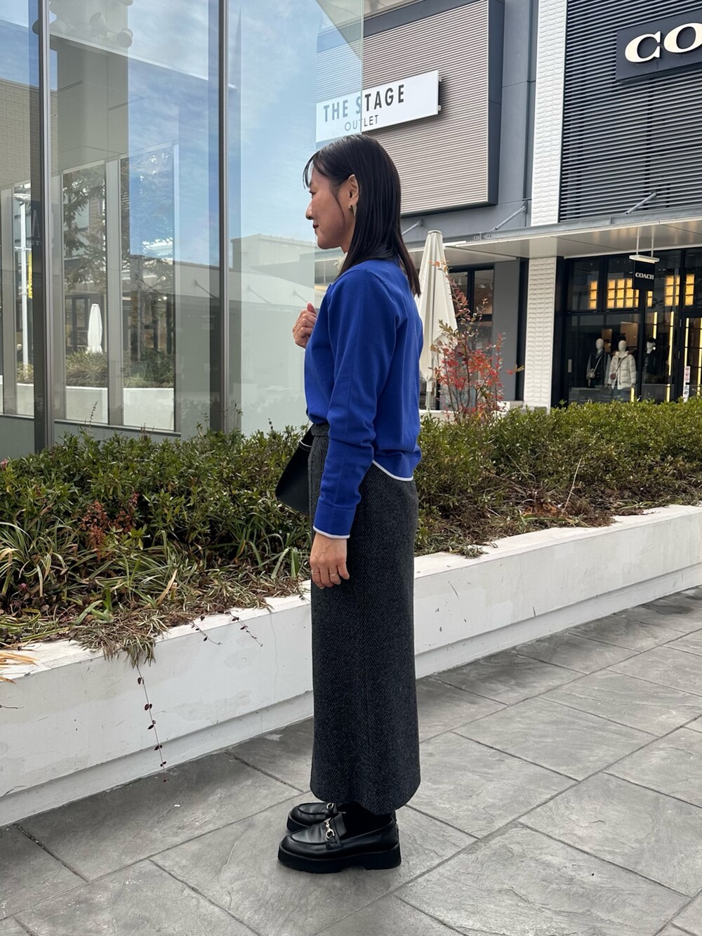 ブルー系のカーディガン/ボレロ、グレー系のスカート、ブラック系のトートバッグを着用したレディースの冬コーディネートの2枚目の写真