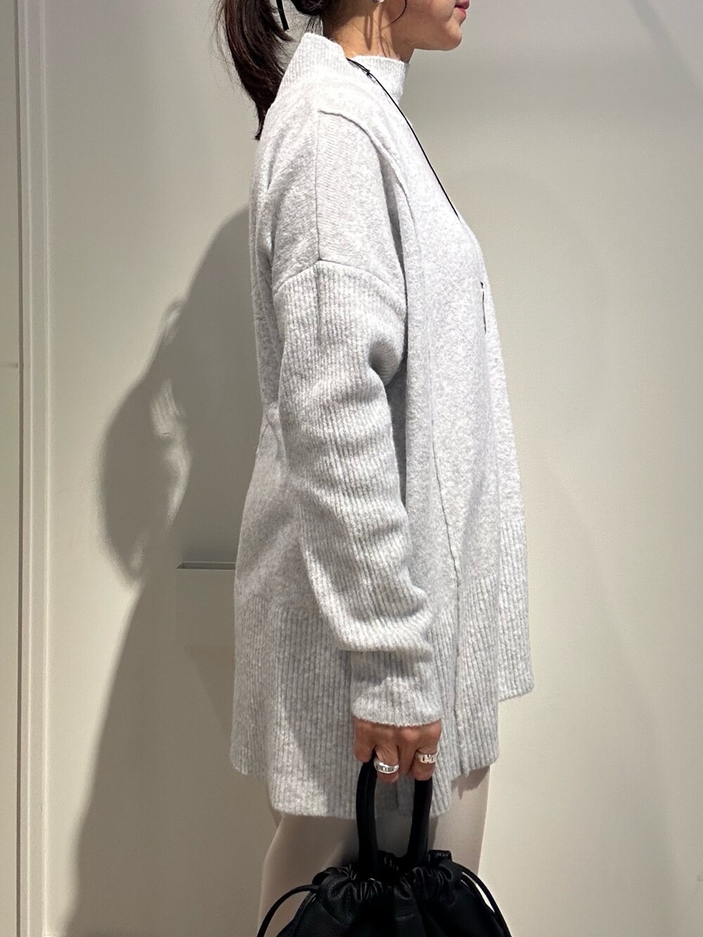 グレー系のニット/セーター、ホワイト系のその他パンツ、ブラック系のショルダーバッグを着用したレディースの冬コーディネートの5枚目の写真