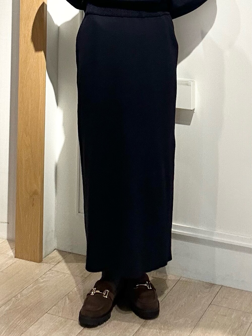 ホワイト系のトートバッグ、ブラウン系のローファー、ブルー系のニット/セーターを着用したレディースの冬コーディネートの6枚目の写真