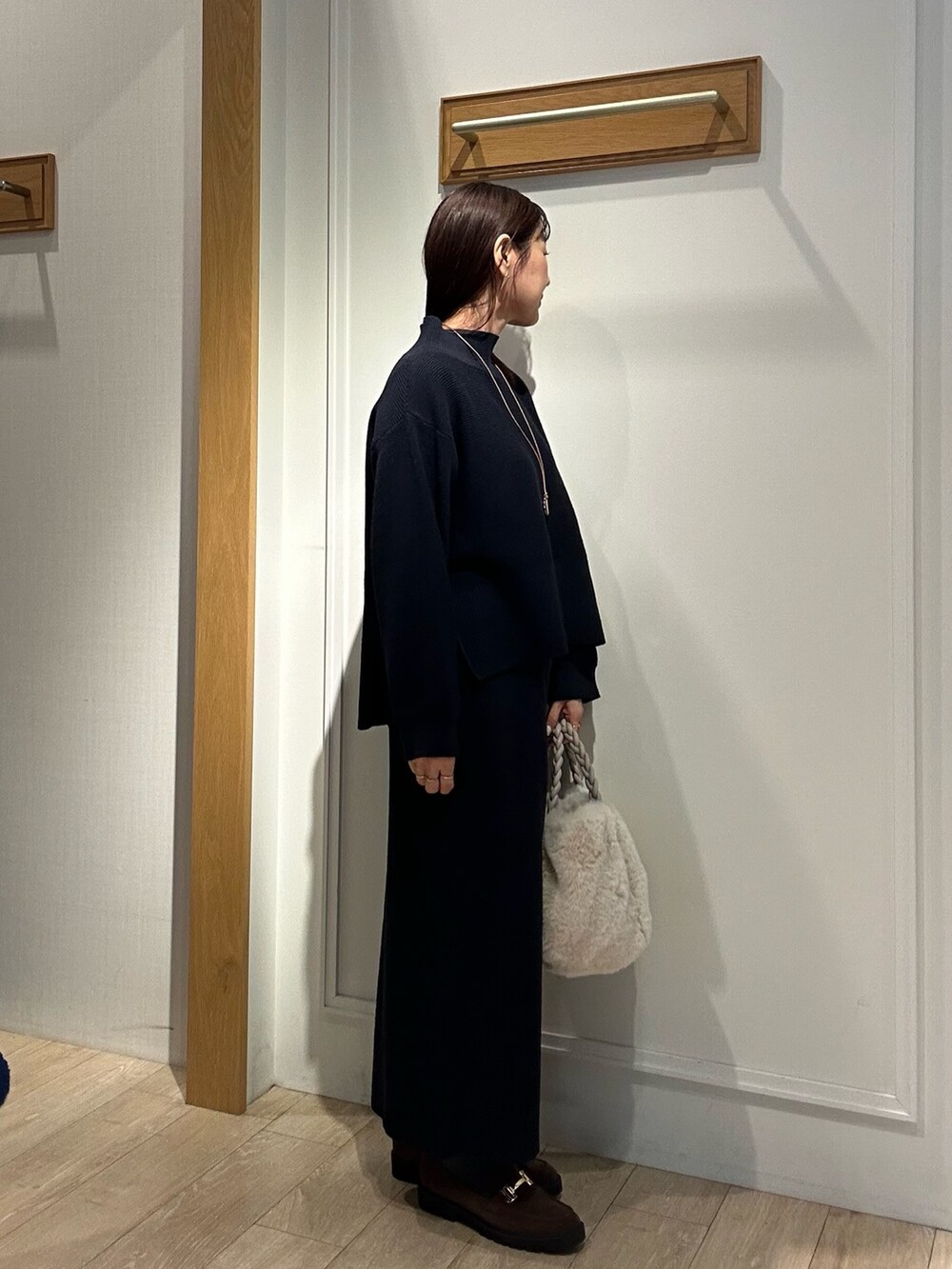 ホワイト系のトートバッグ、ブラウン系のローファー、ブルー系のニット/セーターを着用したレディースの冬コーディネートの4枚目の写真