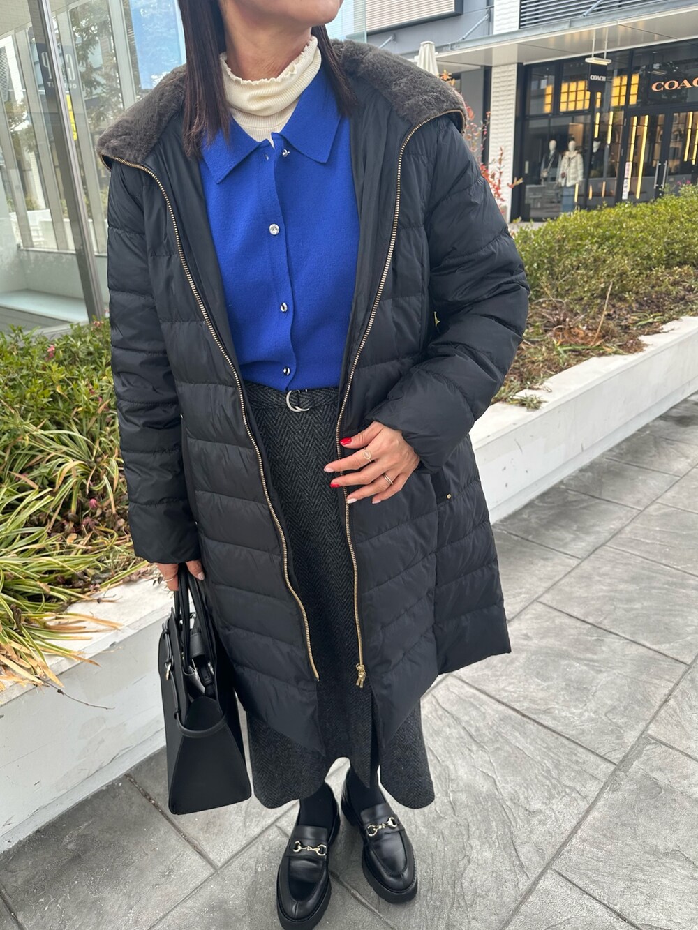 ブルー系のカーディガン/ボレロ、グレー系のスカート、ブラック系のトートバッグを着用したレディースの冬コーディネートの10枚目の写真