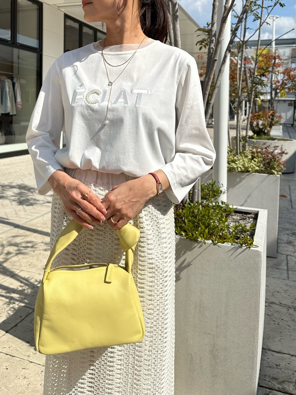 ブルー系のテーラードジャケット、ホワイト系のスカート、イエロー系のショルダーバッグを着用したレディースの春コーディネートの9枚目の写真