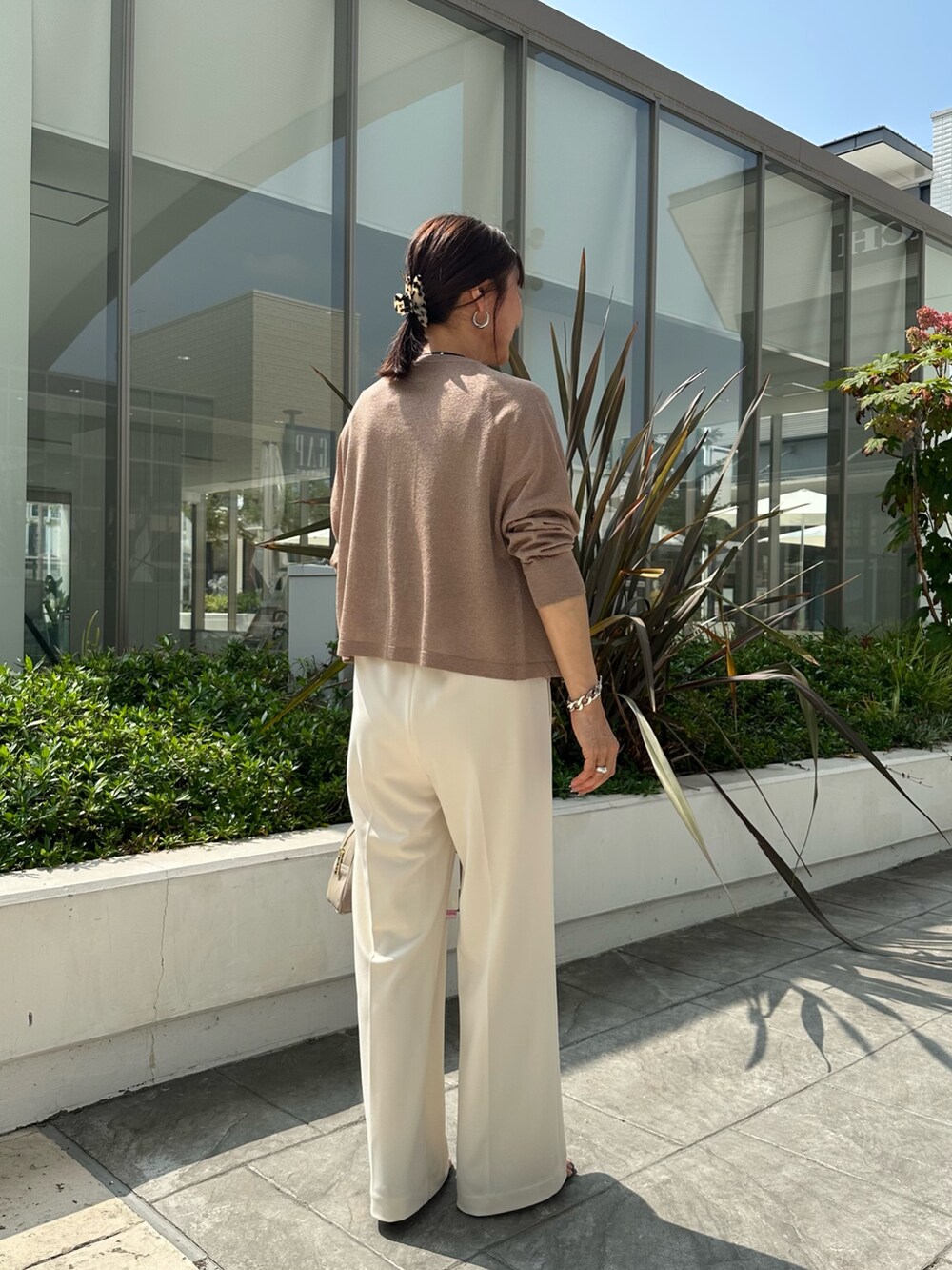 ブラウン系のニット/セーター、ホワイト系のその他パンツ、ベージュ系のボストンバッグを着用したレディースの夏コーディネートの3枚目の写真