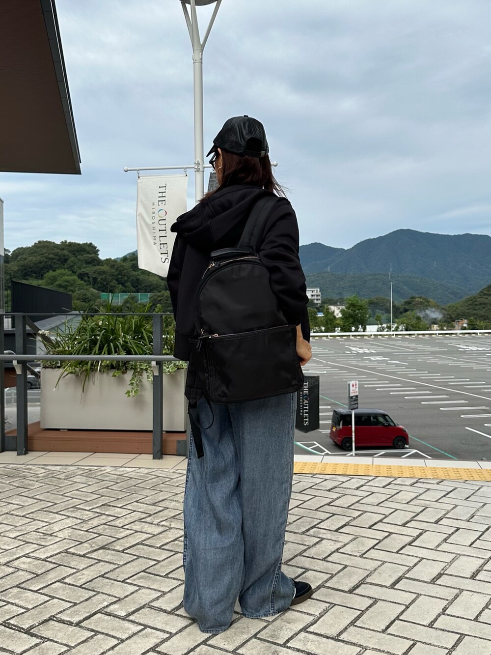 ブラック系のパーカー、ブルー系のデニムパンツ、ブラック系のバックパック/リュックを着用したレディースの秋コーディネートの5枚目の写真