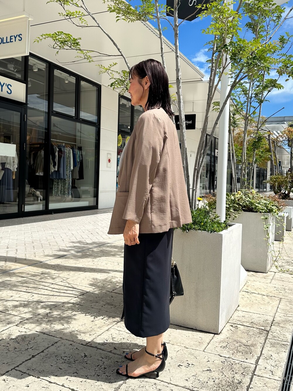 ブルー系のスカート、イエロー系のノーカラージャケット、ベージュ系のシャツ/ブラウスを着用したレディースの夏コーディネートの8枚目の写真