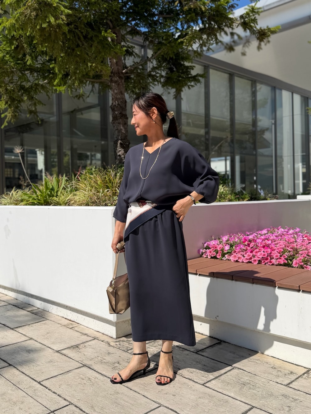 グレー系のシャツ/ブラウス、グレー系のスカート、ベージュ系のショルダーバッグを着用したレディースの夏コーディネートの7枚目の写真