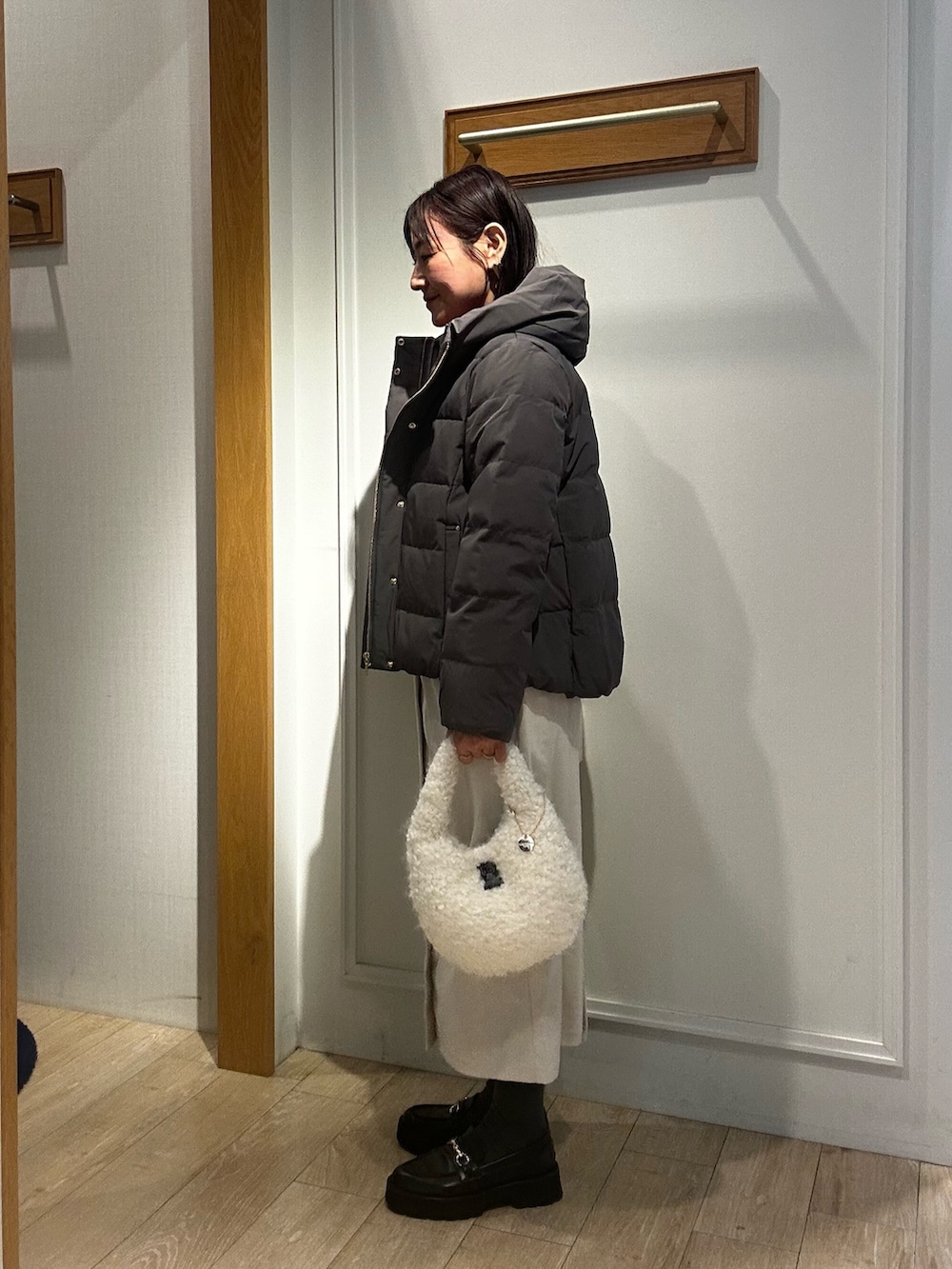 グレー系のダウンジャケット/コート、ピンク系のニット/セーター、ホワイト系のスカートを着用したレディースの冬コーディネートの2枚目の写真