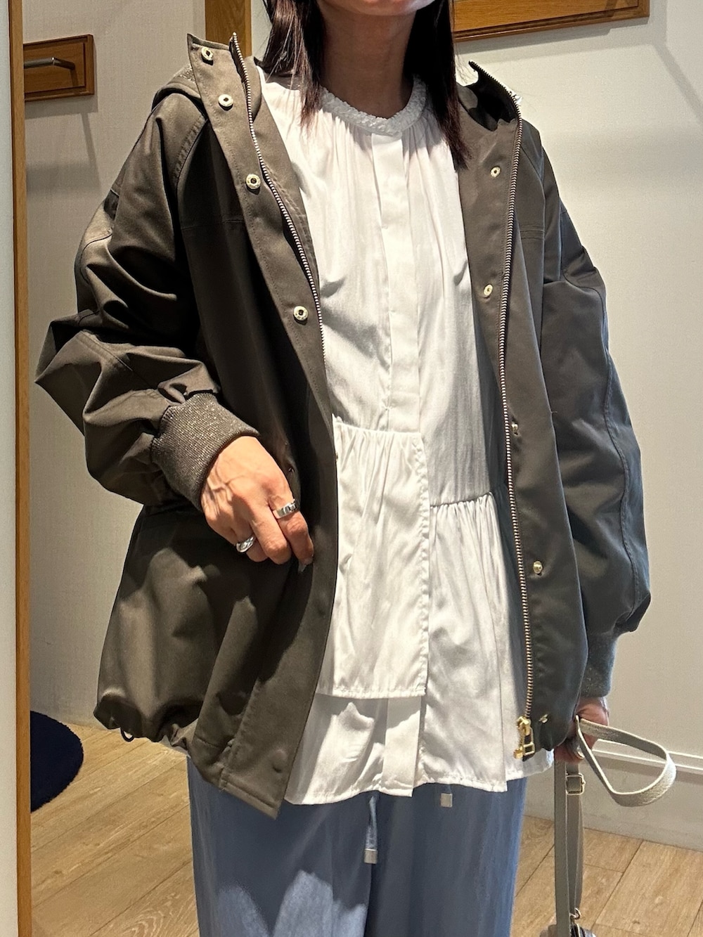 グリーン系のブルゾン、ホワイト系のシャツ/ブラウス、ブルー系のデニムパンツを着用したレディースの冬コーディネートの3枚目の写真