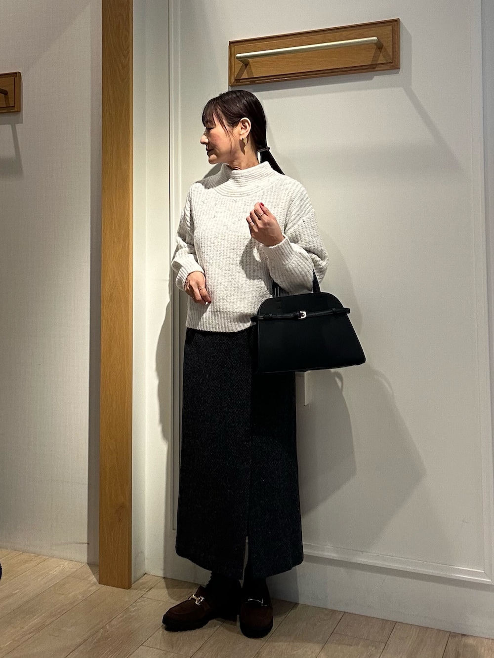 ブラック系のダウンジャケット/コート、グレー系のスカート、ブラック系のトートバッグを着用したレディースの冬コーディネートの6枚目の写真