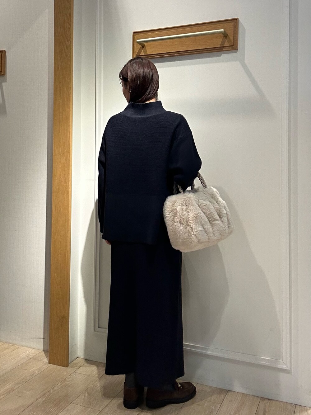 ホワイト系のトートバッグ、ブラウン系のローファー、ブルー系のニット/セーターを着用したレディースの冬コーディネートの3枚目の写真